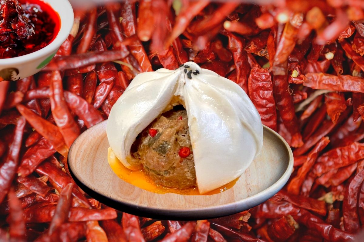 孔子饅頭【剝辣肉包】切面特寫，內餡可見台灣溫體豬肉與老乾媽麻辣醬汁，湯汁飽滿，辣香誘人。