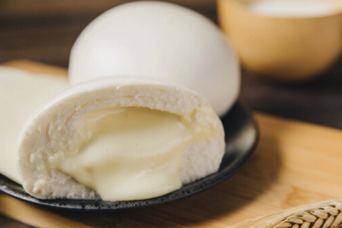 孔子饅頭【孔子-起司包】切面特寫，可見金黃起司內餡與老麵饅頭結合，口感滑順，蛋奶素可食。